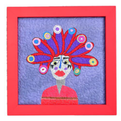 Framed Folk Art. Quilted face on a light blue background with a red frame