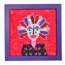 framed folk art featuring a quilted face on a red background with a purple frame